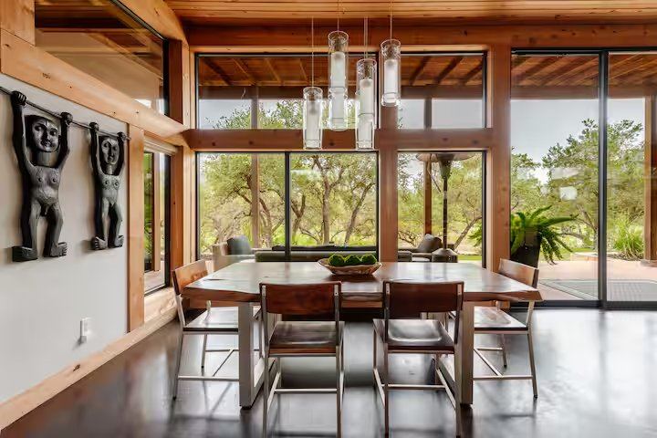 La Paz dining area with live-edge table and Hill Country views through walls of glass
